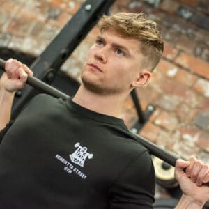 A photo of George holding a barbell on his shoulders