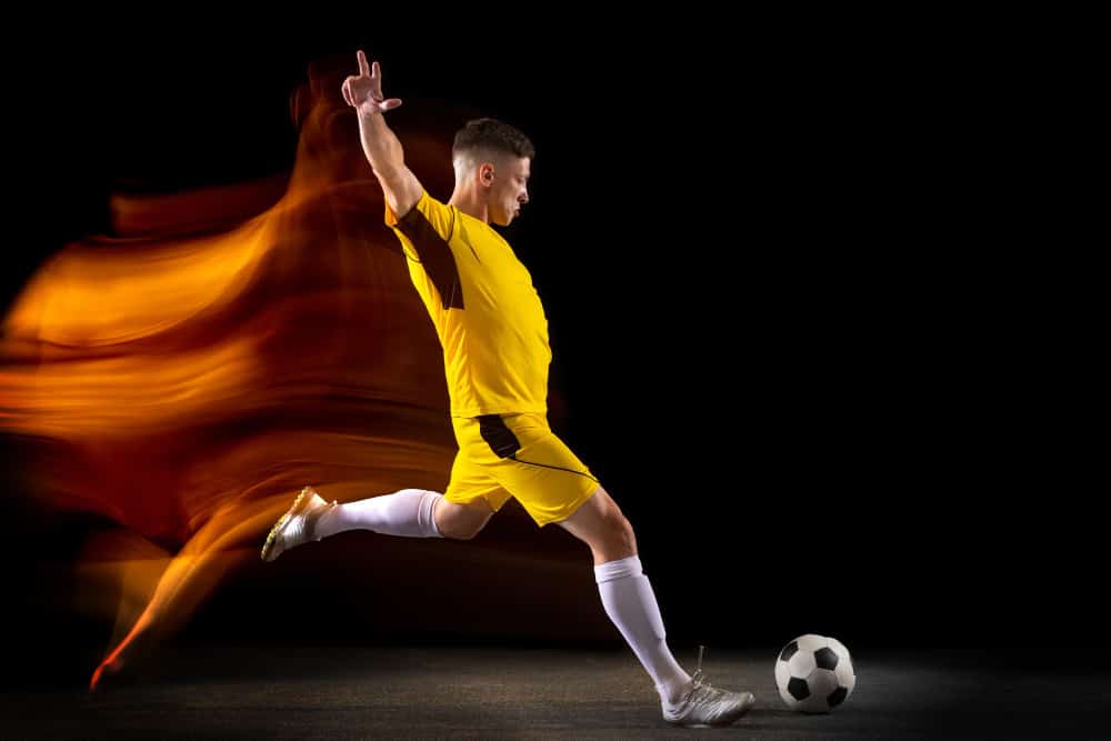 young caucasian male football player kicking ball